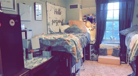 two beds in a dorm room with posters on the wall