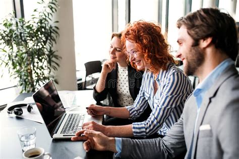 A Group of Young Business People with Laptop Sitting in an Office, Talking. Stock Image - Image ...