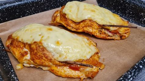 two pieces of chicken covered in cheese on top of wax paper with chopsticks