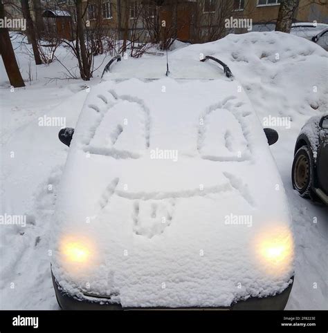 A car covered in snow, with a funny face on the hood. Winter fun Stock Photo - Alamy