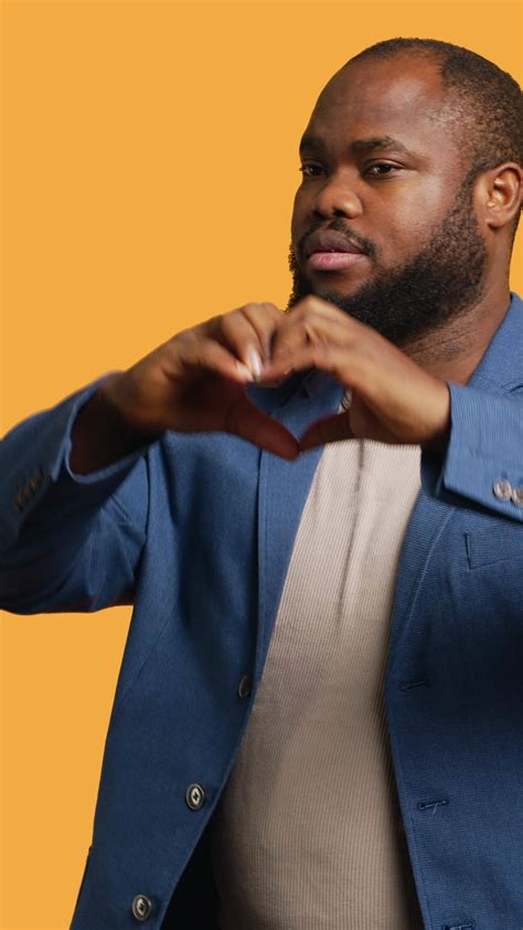 Vertical Portrait of jolly friendly african american man doing heart symbol shape gesture with ...