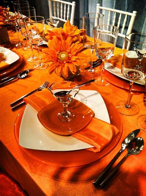 an orange table setting with silverware and flowers