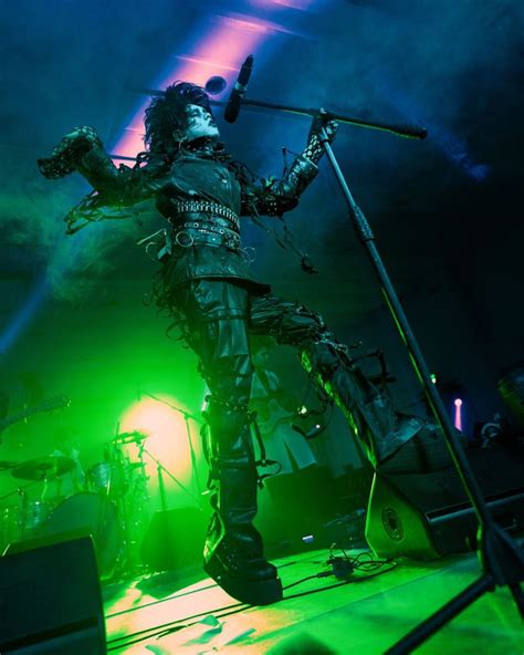 a man standing on top of a stage next to a green and purple light in ...