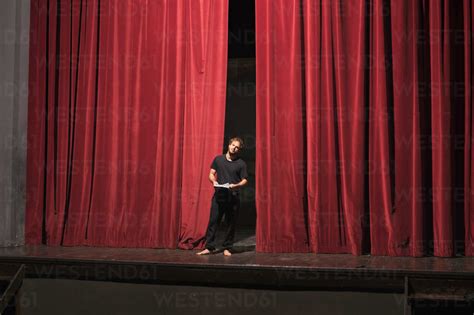 Barefoot actor with script standing on theatre stage stock photo