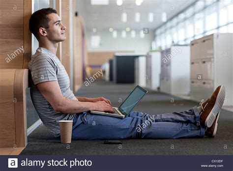 Man sitting on floor using laptop Stock Photo - Alamy