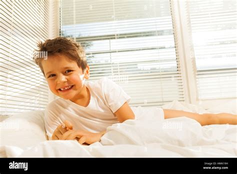 Cute kid boy smiling while lying on his bed Stock Photo - Alamy