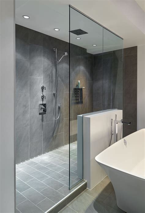 Large walk-in doorless shower with gray slate tiles and a floating glass wall creates a gorgeous ...