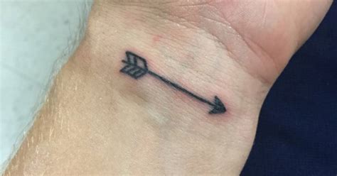 Small arrow tattoo on the wrist.