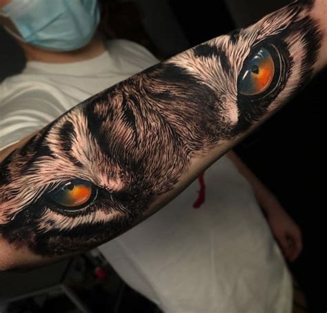 a person with a mask on their face has a cat's eye tattooed on his arm