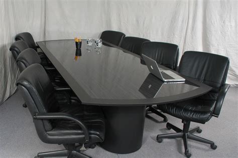 Long rectangle black glass conference table added by black leather swivel chairs on the floor