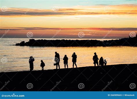 Silhouette of a Group of People Enjoying a Colorful Sunset on Seashore ...