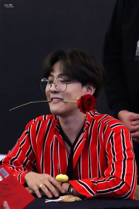 a man in red and black striped shirt sitting at table with flower on his nose