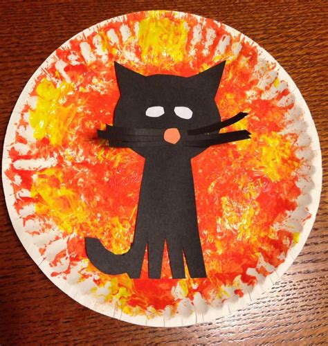 a paper plate with a black cat painted on it's face and flames in the ...