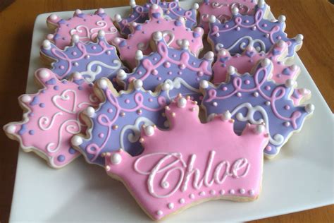 decorated cookies with tiaras and pearls are on a white plate that says, alice