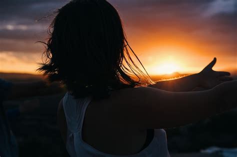 Premium Photo | A woman points at the sunset in the mountains