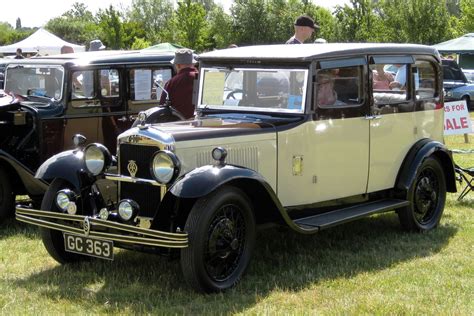 an old car is parked in the grass with other antique cars behind it and ...