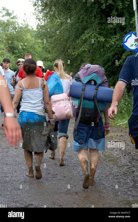 People walking barefoot in flooding water and mud following heavy rain at Glastonbury Festival ...