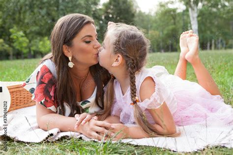 Mother and daughter kissing on the lips, having fun on a picnic at the park Stock-Foto | Adobe Stock