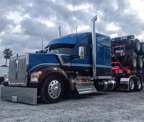 a blue semi truck parked on top of a dirt field