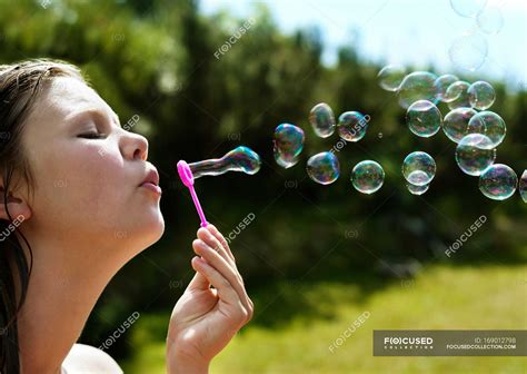 Girl blowing bubbles outdoors, focus on foreground — sunlight, nature ...