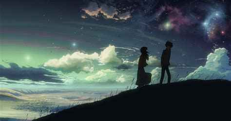 two people standing on top of a hill looking at the stars in the night sky