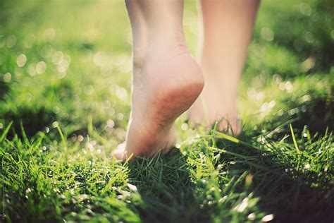 Walking barefoot across the grass. by Kitty Kleyn - Stocksy United