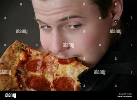 Young man eating a slice of pizza Stock Photo - Alamy