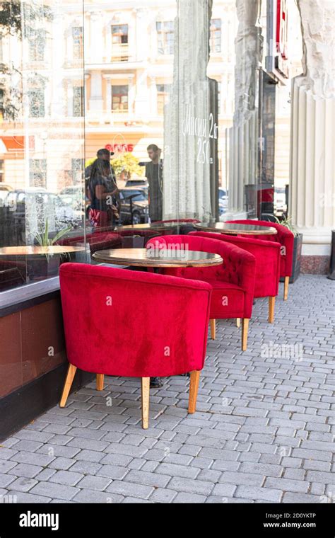 Street cafe, stylish minimalistic empty tables with beautiful red velvet chairs in an outdoor ...