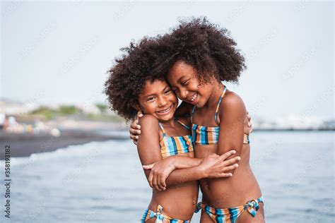 Black sister twins having fun on the beach during summer time - Little female kids laughing and ...