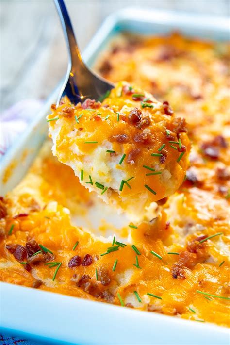 a spoon scooping some food out of a casserole dish with cheese and bacon