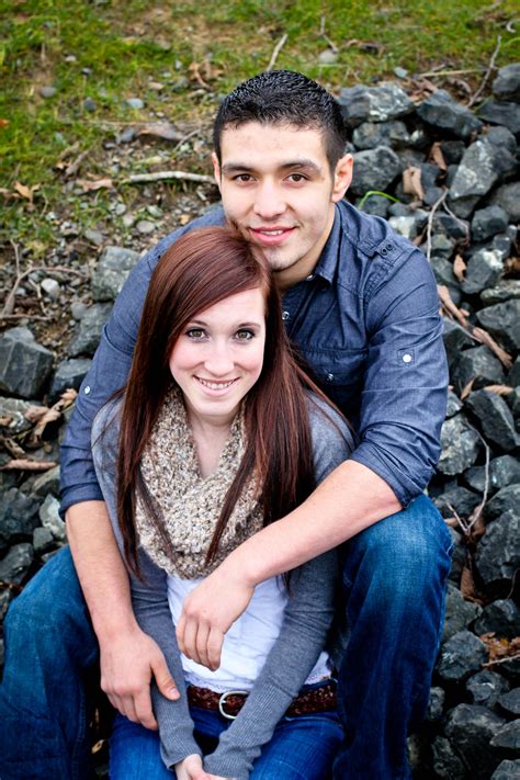 a man and woman sitting next to each other in front of some rocks on the ground