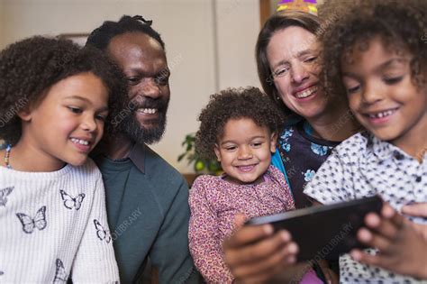 Happy multiethnic family using smart phone - Stock Image - F030/2243 ...