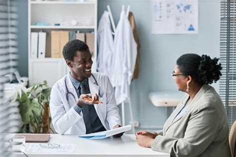 Premium Photo | Smiling black doctor talking to woman during consultation in clinic