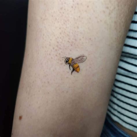 a small bee tattoo on the thigh