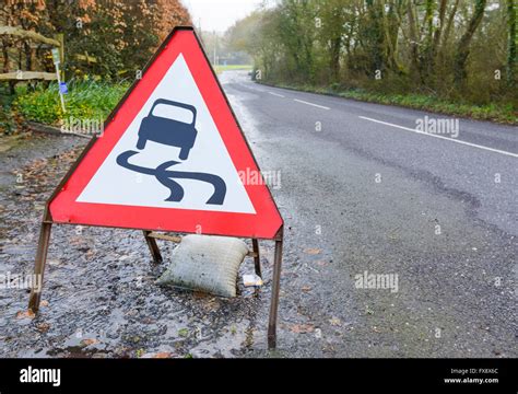 Slippery road triangular warning sign on a flooded road in the UK Stock Photo - Alamy