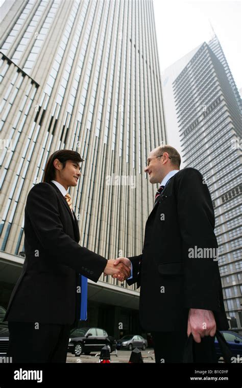 two businessmen from different cultures handshaking and talking in the sreet in Shanghai,China ...