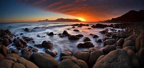 Premium AI Image | A sunset over the ocean with rocks and a sunset in ...