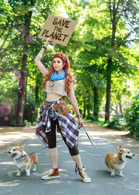 a woman with red hair holding a sign while standing next to two dogs on ...