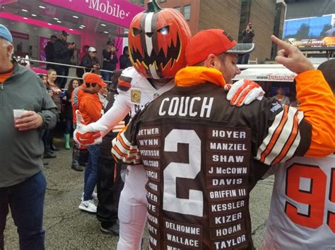 two cleveland browns fans wearing orange and white jerseys are standing ...