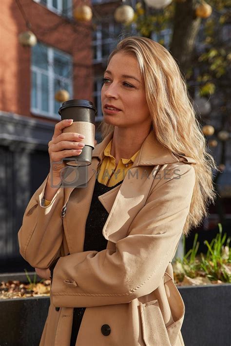 caucasian attractive woman in beige trench coat holding cup of coffee outdoors #Ad , #holding, # ...