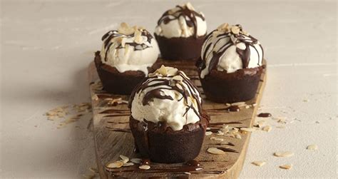 chocolate cupcakes topped with whipped cream and nuts