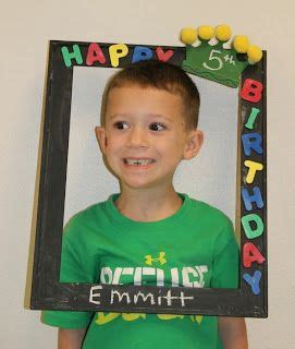 a young boy wearing a green shirt and holding up a birthday photo frame