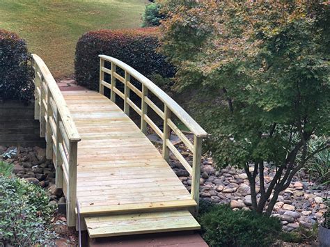 Arched, wooden bridge over dry creek bed. Designed and built by Atlanta Decking & Fence ...