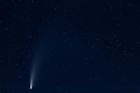 A comet with a large dusty glowing tail in the night sky. Comet Neowise over the TV tower ...
