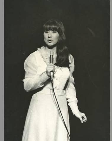 an old photo of a woman holding a microphone in her right hand and ...