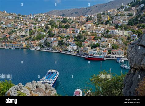 Symi Harbour with neoclassical buildings and fishing boats Stock Photo - Alamy