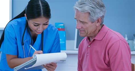 Female nurse talking to senior male patient and taking medical history ...