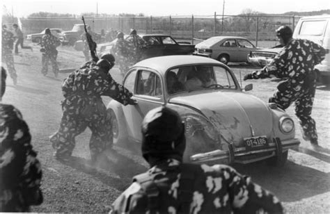 men in camouflage standing near an old car