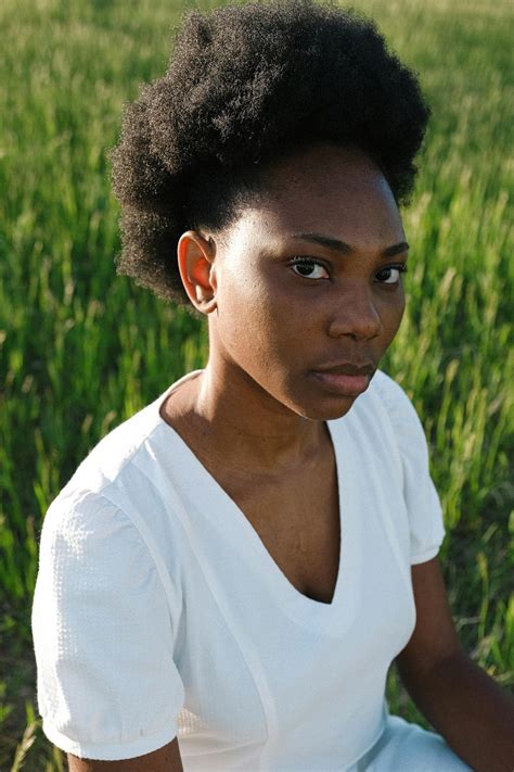 Woman in White V Neck Shirt Standing on Green Grass Field · Free Stock Photo