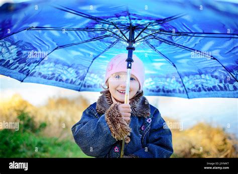 Little girl and boy with umbrella playing in the rain. Kids play ...